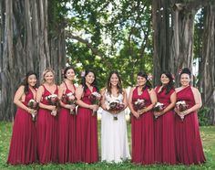 a group of women standing next to each other in front of some trees and grass