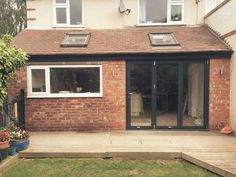 a house that has a wooden deck in front of it and windows on the side