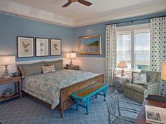 a bed room with a neatly made bed next to two chairs and a table in front of a window