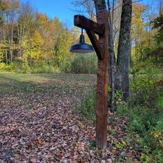 a wooden pole with a lamp hanging from it's side in the middle of leaves