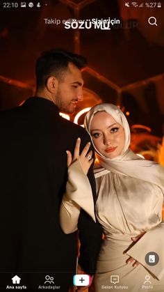 a man and woman standing next to each other in front of a building with lights