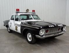 an old black and white police car parked in a garage