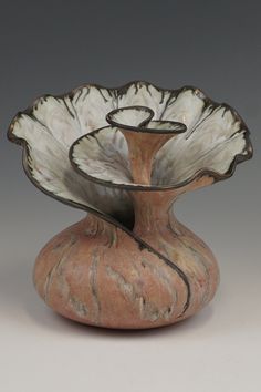 a white and brown vase sitting on top of a table