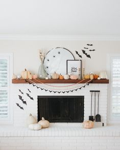 a living room decorated for halloween with bats, pumpkins and other decorations on the mantel