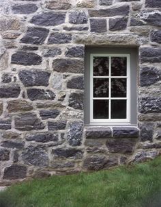 a stone building with a window and grass