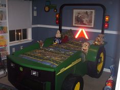 a green tractor bed sitting inside of a bedroom next to a wall with pictures on it