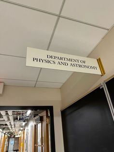 a sign that says department of physics and astronomy hangs from the ceiling in an office