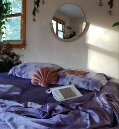 an open laptop computer sitting on top of a purple comforter in a room with potted plants