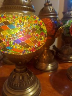 an assortment of colorful mosaic glass vases on a wooden table with other decorative items in the background