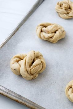 four doughnuts on a baking sheet ready to be baked into buns or pretzels