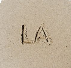 the word la is written in sand with an arrow drawn on it's side