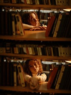 a woman sitting at a table in front of a bookshelf filled with books