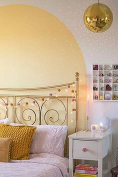 a bedroom with a white bed and gold accents on the headboard, night stand and nightstand