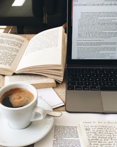 an open book next to a cup of coffee on top of a white saucer