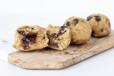 three chocolate chip muffins on a wooden cutting board with one cut in half