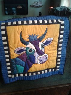 a quilted cow is hanging on the back of a couch