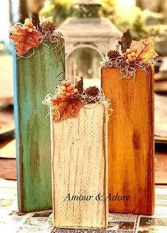 three wooden vases sitting on top of a table next to each other with autumn decorations