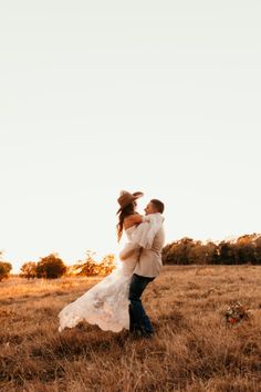 a bride and groom are dancing in the field