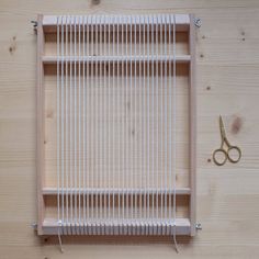 a pair of scissors sitting on top of a piece of wood next to a weaving loom