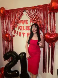 a woman in a red dress standing next to balloons and streamers with the number twenty two