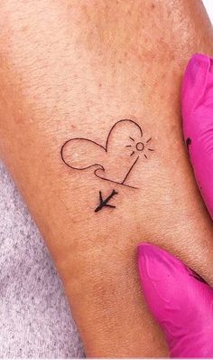 a woman's arm with a heart and an arrow tattoo on her left side