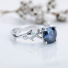 a blue ring sitting on top of a table next to some branches and flowers with leaves