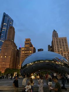 many people are walking around in the city at night, with skyscrapers in the background