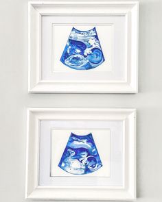 two framed pictures with blue vases in them on a white wall next to each other