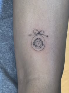 a woman's arm with a small tattoo of a lion in a round frame