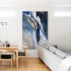 a living room filled with furniture and a painting hanging on the wall over a wooden table