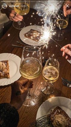 people sitting at a table with wine glasses and desserts in front of sparklers