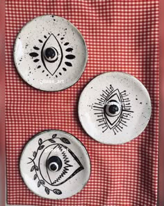 three plates with designs on them sitting on a red and white checkered table cloth