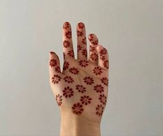 a person's hand with red flowers painted on it and the palm of their left hand