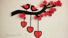 a paper bird sitting on top of a tree branch with hearts hanging from it's branches