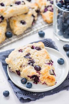 blueberry muffins on a white plate next to some fresh blueberries