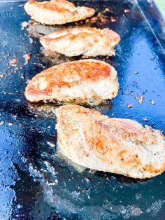 four pieces of meat cooking on a grill