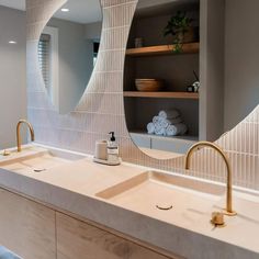 a bathroom with two sinks and a large mirror above the sink is an open shelving unit