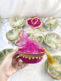 a hand is holding a pink and green bowl with gold trimmings on it