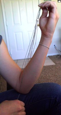 a woman is sitting on the floor with her arm wrapped around wires in front of her