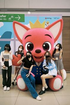 a group of people standing next to a giant stuffed animal