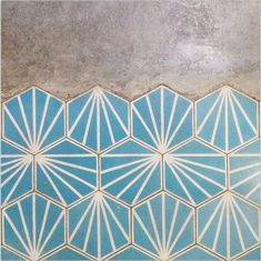 a blue and white tiled wall with geometric designs on the bottom, in front of a concrete floor