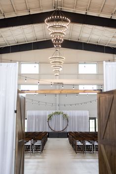 the inside of a church with rows of wooden pews and chandeliers hanging from the ceiling