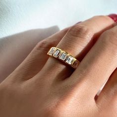 a woman's hand wearing a gold ring with three baguettes on it