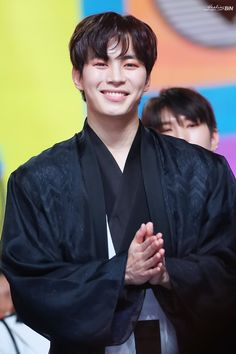 the young man is wearing a black kimono and holding his hands together in front of him