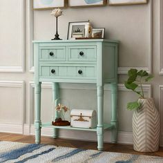 a blue table with two pictures on the wall and a potted plant next to it