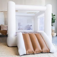 an inflatable bed is set up on the floor next to a chair and potted plant