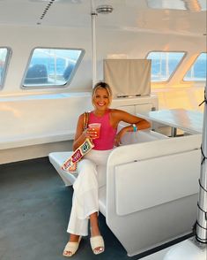 a woman sitting on the back of a boat holding a drink