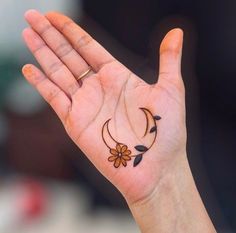 a person's hand with a small tattoo on the middle of their left palm