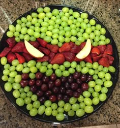 grapes, strawberries and apples arranged in the shape of a face on a plate