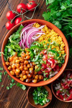 a large bowl filled with vegetables on top of a wooden table next to two small bowls